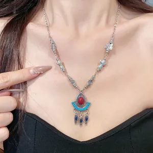 Detailansicht einer Vintage-Boho-Halskette mit rotem Harzstein und blauen Quastenanhängern.