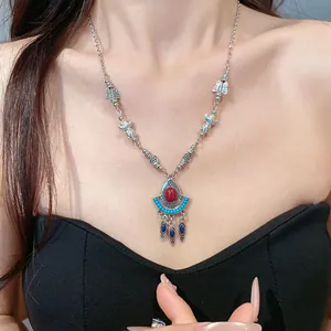 Nahaufnahme einer böhmischen Quastenkette mit rotem Harz und blauen Perlen am Modell.
