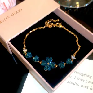 Close-up of 18k gold plated bracelet featuring blue heart-shaped zircons in a clover design.