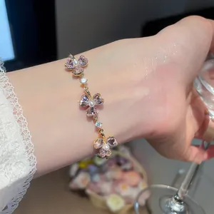 Detailed macro view of an elegant 18k gold plated zircon and pearl clover bracelet worn on wrist
