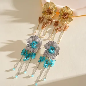 Detailweergave van metalen bloemen oorbellen met turquoise glazen kralen kwastjes.