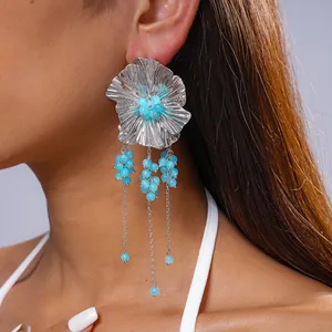 Detail van vintage zilveren bloemoorbellen met kwastjes van blauwe glazen kralen.