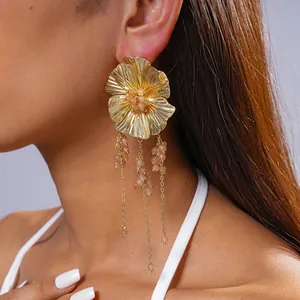 Detailopname van gouden bloemoorbellen met kralenkwastjes aan het oor van een model