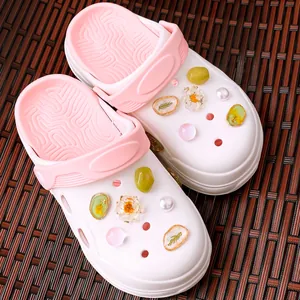 Detail van witte en roze clogs versierd met bedeltjes van harsbloemen en parels