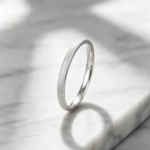 Detail view of elegant silver frosted titanium steel ring on a white marble slab surface