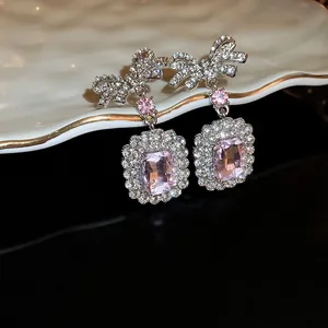 Prachtige zilveren strik oorbellen met roze rechthoekige edelsteen en zirkonia accenten.
