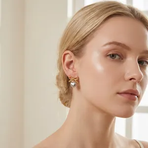 Close-up detail of a female model wearing elegant gold bow and silver heart pendant earrings