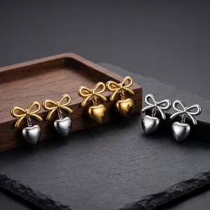 Close-up detail of stainless steel bow heart earrings in polished gold and silver finishes