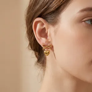 Close-up of a stylish gold-plated stainless steel earring with bow and heart