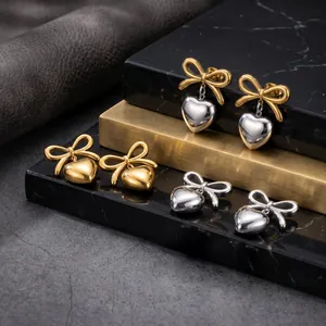 Detailed view of elegant bow heart earrings in gold and silver finishes on marble