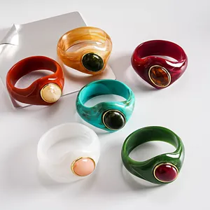 Dettaglio di sei bracciali rigidi in acrilico marmorizzato con pietre ovali in vari colori vivaci