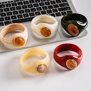 Varietà di bracciali in acrilico con texture marmorizzata e inserti ovali color ambra