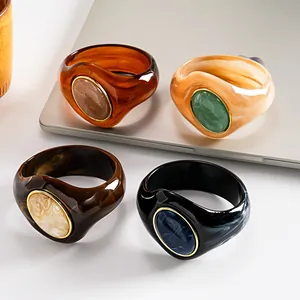 Primo piano di quattro bracciali rigidi in acrilico marmorizzato con pietre ovali