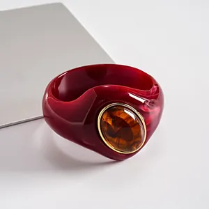 Dettaglio macro di bracciale in acrilico rosso venato con pietra in resina ambrata