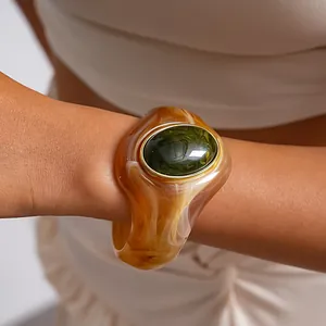 Dettaglio macro di un grande bracciale in acrilico ambrato con pietra ovale verde