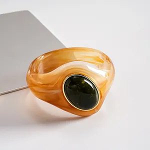 Dettaglio di un bracciale rigido in acrilico marmorizzato con pietra ovale verde