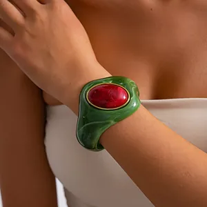 Primo piano di un bracciale a polsino in acrilico marmorizzato verde con pietra rossa