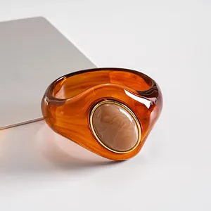 Primo piano di un bracciale in acrilico ambrato con intarsio marmorizzato e bordo dorato