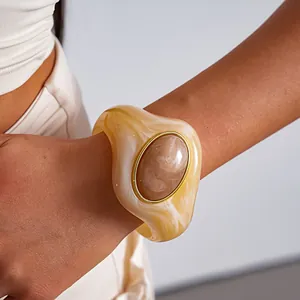 Vista dettagliata di un bracciale rigido in acrilico marmorizzato giallo con centro ovale oro