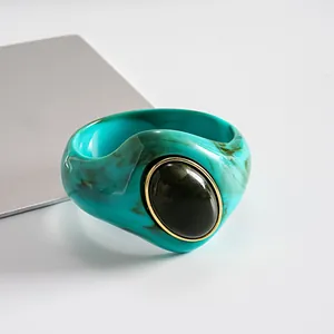 Dettaglio macro del bracciale in acrilico turchese marmorizzato con pietra nera ovale