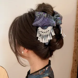 Detailed view of an ethnic embroidered hair clip with silver tassels in dark hair