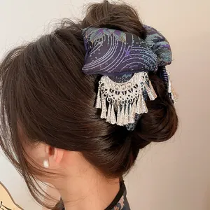 Side view detail of an ethnic style hair claw with intricate embroidery and silver tassels
