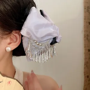 Detail view of a lilac silk hair claw clip with vintage silver tassels and embroidery