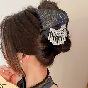 Close-up of navy blue ethnic hair claw clip with gold embroidery and silver tassels.