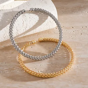 Détail d'un collier choker en métal tressé minimaliste en tons argent et or poli.