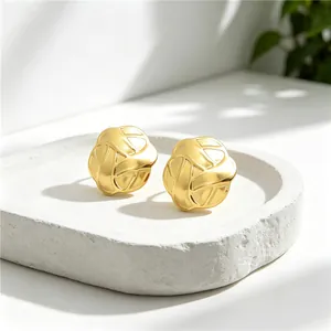 Close-up of high-quality gold stainless steel woven knot stud earrings on white stone tray