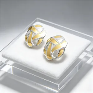 Close-up of gold and silver two-tone stainless steel lattice stud earrings on display