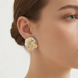 Close-up detail showing the elegant two-tone gold and silver braided knot stud earrings