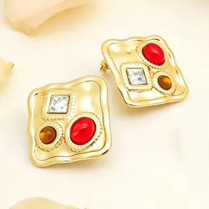 Détail de boucles d'oreilles carrées dorées vintage avec des pierres multicolores