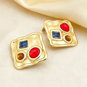 Gros plan de boucles d'oreilles carrées plaquées or avec pierres colorées.