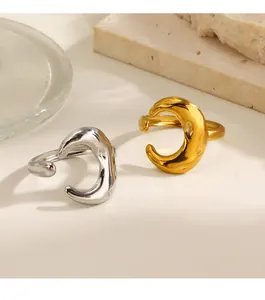 Detail view of silver and gold crescent moon open rings on neutral stone background