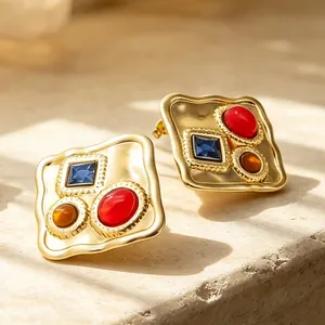 Gros plan de boucles d'oreilles carrées dorées avec des pierres colorées