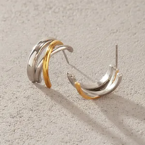 Detail view of two-tone gold and silver layered titanium steel stud earrings for women