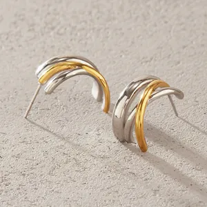 Detailed view of triple-layered C-shape stud earrings with gold and silver polished finish
