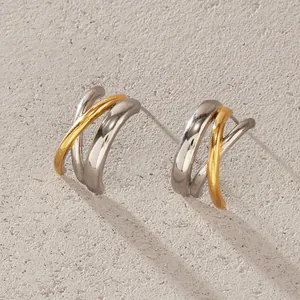 Macro view of bi-color silver and gold stainless steel crossed hoop stud earrings