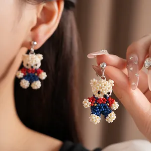 Handmade beaded bear earrings featuring a vibrant cream, red and blue color palette