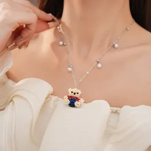 Close-up view of a handcrafted beaded teddy bear necklace with elegant pearls on a model.