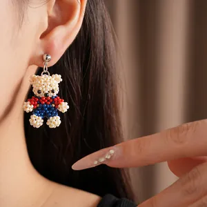 Detailed view of a handmade colorful beaded bear earring worn by a model in lifestyle shot