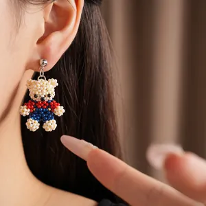 Detailed macro view of a handmade beaded teddy bear earring worn on a model's ear