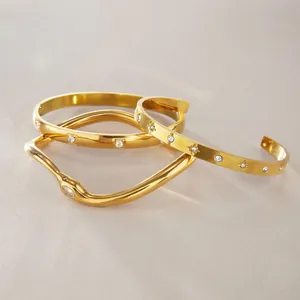 Vista dettagliata di tre bracciali in oro e acciaio al titanio con pietre di zircone