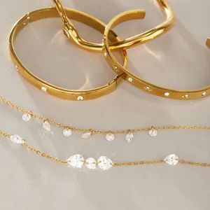 Dettaglio di bracciali in acciaio dorato e collana con pietre CZ trasparenti