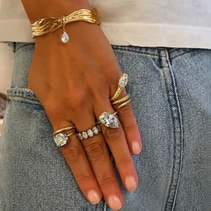 Close-up of gold titanium steel bangle with zircon pendant and stacked rings on hand