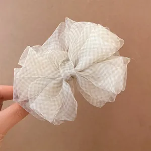 Dettaglio dell'elegante fermaglio per capelli con fiocco in velo di neve e motivo a scacchi