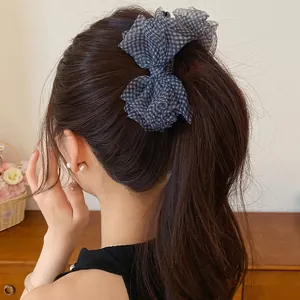 Vista dettagliata di un fermaglio per capelli a fiocco in chiffon a scacchi su una coda alta
