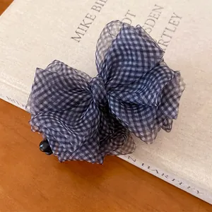 Dettaglio di un fermaglio per capelli a fiocco in organza a quadri su un libro