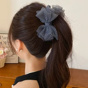 Dettaglio di un elegante fermaglio per capelli con fiocco a quadretti bianco e nero.